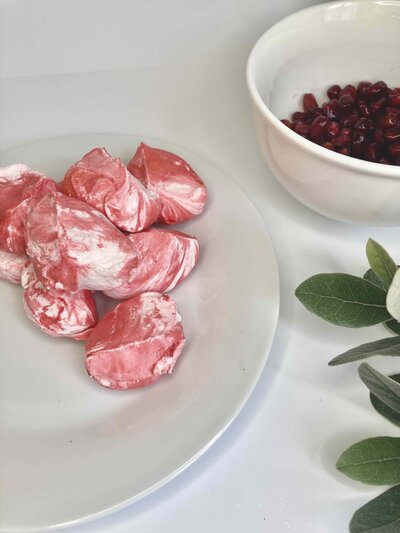 Bright pink and white swirled meringue cookies on white plate.