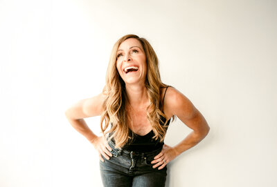 Branding portrait of Shannon O'Malley, Minneapolis-based online dating photographer, smiling with hands on hips, showcasing her confident and encouraging presence for clients.