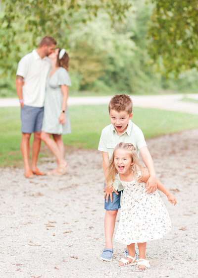 Kids share silly expression upon seeing parents share a kiss at Johnson Park in Walker MI, West Michigan Family Photography.