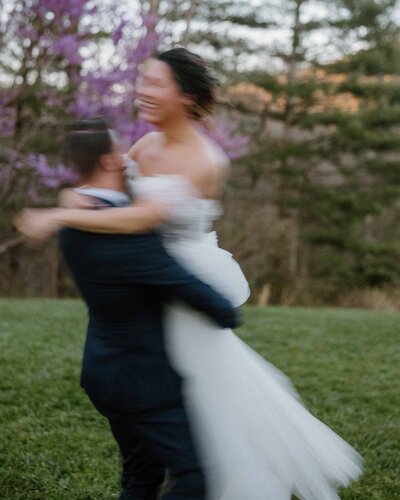 Groom spinning his bride in a field and blurry