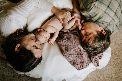 Newborn resting peacefully on mother’s chest in soft window light, swaddled in a dotted muslin wrap during a calm, baby-led session in Portland.