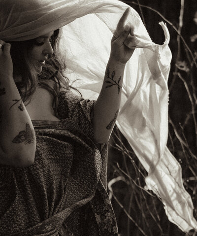 Young cowboy couple walk through a field in the setting sun in thrifted wedding attire.