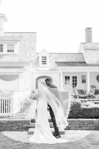 bride and groom looking into each other's eyes with veil blowing in the wind