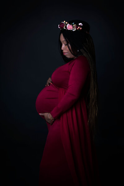 Maternity and Newborn gallery photo of pregnant black woman in red dress with a flower wreath on her head  photo by Jessica Stewardson