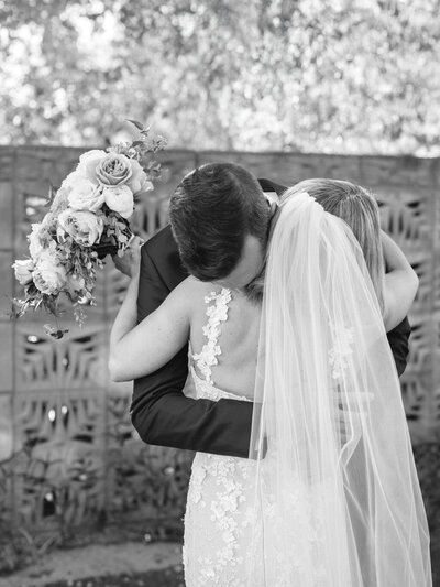 Wedding photography in Phoenix capturing a stunning moment as a bride and groom step out of a white brick tunnel at a fine art wedding venue.