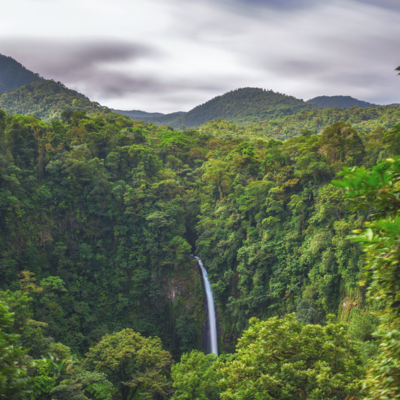 Lush green jungle in Costa Rica with mountains in the background, and a waterfall amid the greenery