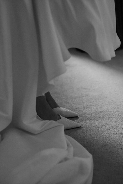 Close-up shot of a bride's sparkling shoes under the folds of her wedding gown