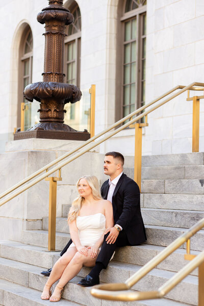 Couple sitting on stairwell during engagement photoshoot  