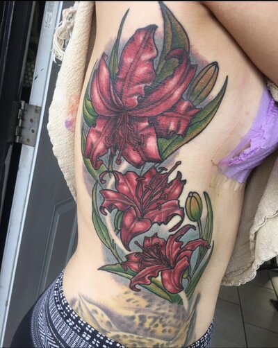 Pink floral tattoo in man's shin