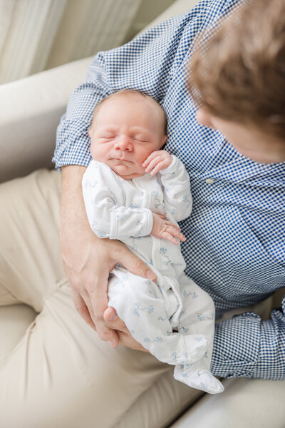 Newborn being cradled in his father's arms.