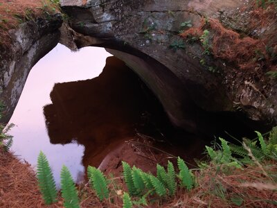 Sandstone archway over river reflection and sand