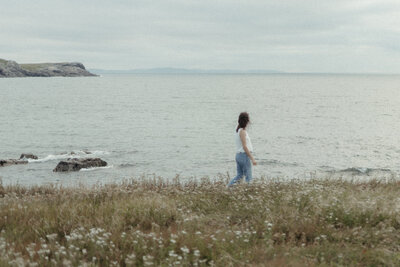 Heather looks out to sea in a meadow of tall grass