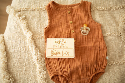 newborn clothes with wooden milestone card