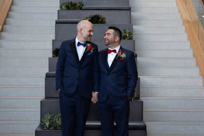 Two men in tuxedos standing in front of stairs captured by an Austin-based wedding photographer.