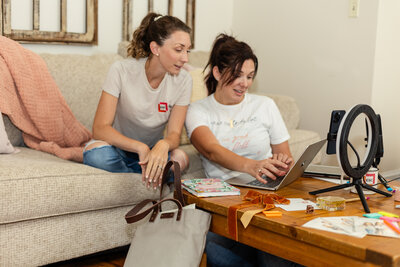 A shot from a photoshoot where a woman in jeans and a long sleeve Tshirt sits on a kitchen counter