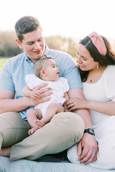 Family with six month old sitting in grassy field