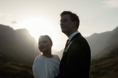 Couple hold hands on top of a mountain during sunset after their elopement in Glencoe, Scotland