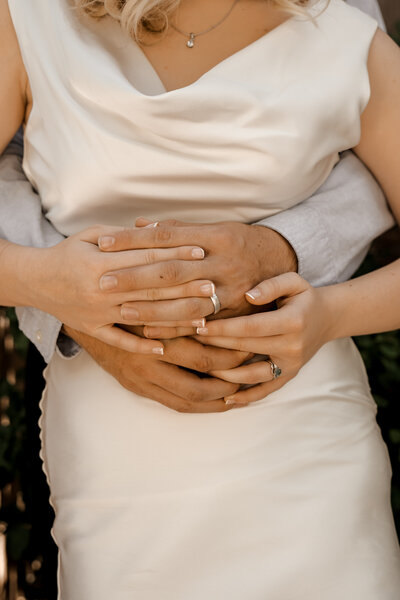 Romantic couple clasping hands around each other. Rings shining bright.