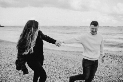 out of focus black n white, B & T holding hands running along the beach