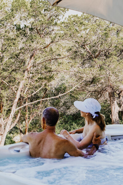 Man and woman sitting in a hot tub looking at trees