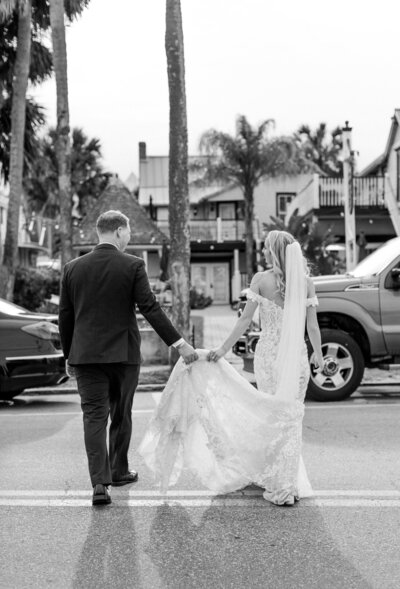 black and white photo bride and groom walking across st. augustine street