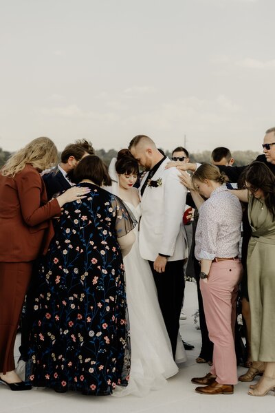 Family members lay hands on the bride and groom to pray for them during the ceremony.