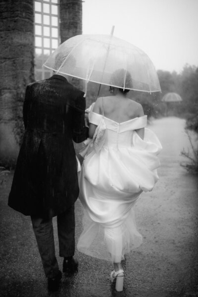Nass, aber glücklich ist dieses Hochzeitspaar im Regen auf dem Weg in ihre gemeinsame Zukunft.