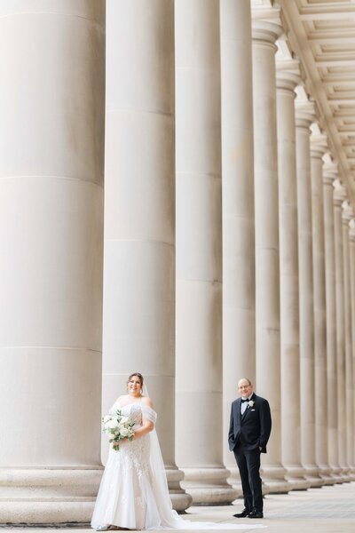 Engaged couple sitting together on the elegant white marble staircase of the Rookery Building in Chicago, holding hands and sharing a quiet moment against the historic wood-carved backdrop.