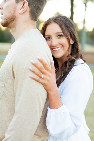 engaged woman smiling with her hand on her fiance's shoulder