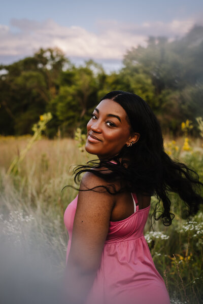 A young women in a pink dress smirking 