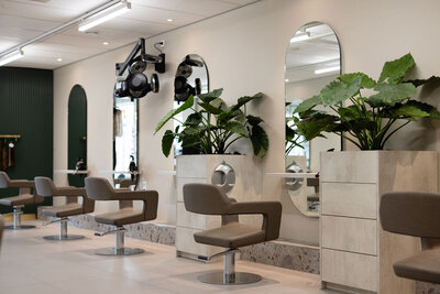 Een frisse, open salon met slimme indeling en sfeervolle accenten zoals spiegels op maat en geïntegreerde planten.
