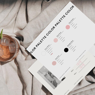 Curated workspace with a collection of photos, glass of wine, and hands selecting design elements, illustrating the premium brand creation process for upscale clients in Houston, TX.