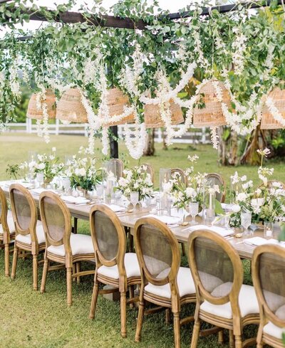 Rustic outdoor Kauai wedding table setting with decorated greenery, fresh flowers, and hanging white flowers 
