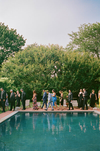 Wedding guests cocktail hour by the pool at private residence wedding in the hamptons new york, East coast documentary-style wedding photographer for the untraditional