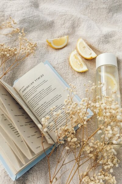 Peaceful wellness scene with hormone health book, lemon water, and flowers—supporting hydration, education, and balance during menopause