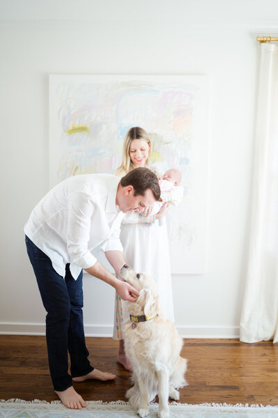 Mother sitting on bed cradling baby during a natural light newborn portrait session