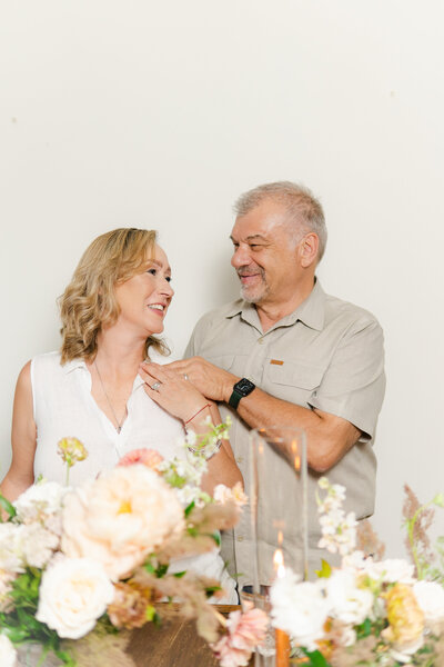 Sothern california floral studio  founder couple looking at each other in front of floral centerpiece design