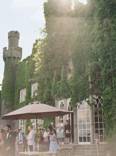 Candid film images of guests mingling during cocktail hour out on the patio at Luttrellstown Castle