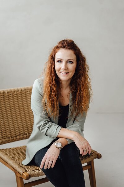 Lachende Frau sitzt auf einem Hocker im Atelier