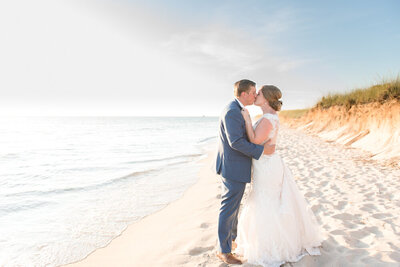 couple kissing on Lake Michigan beach at sunset during their Ludington Michigan wedding