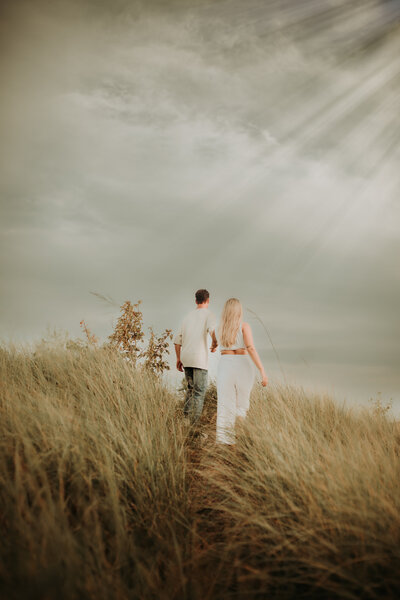 Beautiful photo of couple walking away in sand dunes at sunset. Emily McCracken Photography, Grey Bruce Photographer, Specializing in weddings, elopements, Southampton, Ontario