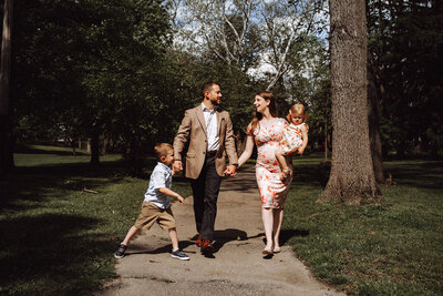 A family in semi-formal wear walks through a park.