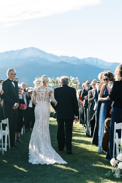 bride walking down the aisle with her father and a backdrop of colorado springs mountains by Colorado Wedding Photographer JKG Photography