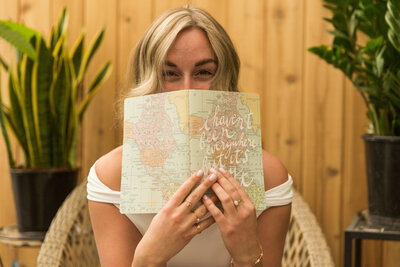 Jessie holding her travel journal covering her face
