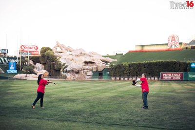 Engaged couple playing catch at Angel Stadium