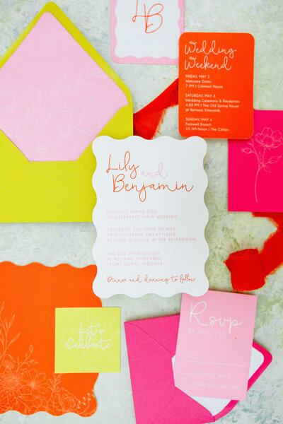 Modern colorful wedding stationery suite featuring bold coral and green designs, floral details, and custom die-cut pieces.