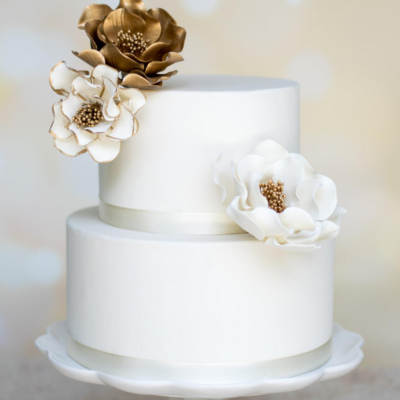 Two tier cake displaying a  Sugar flower bundle of Hand painted gold Open roses