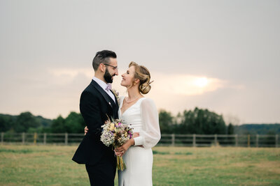 A bride and groom at a summer wedding look at each other with love. Boho wedding