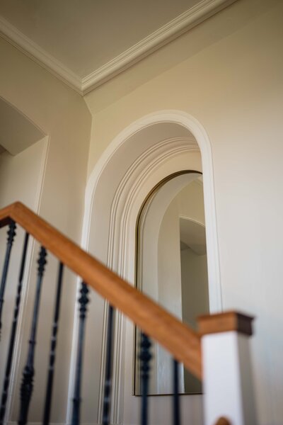 A mirror is photographed above a staircase in Kinclune Houe. The space is bright and airy.