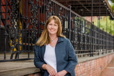 Branding photo of a woman standing next to a railing